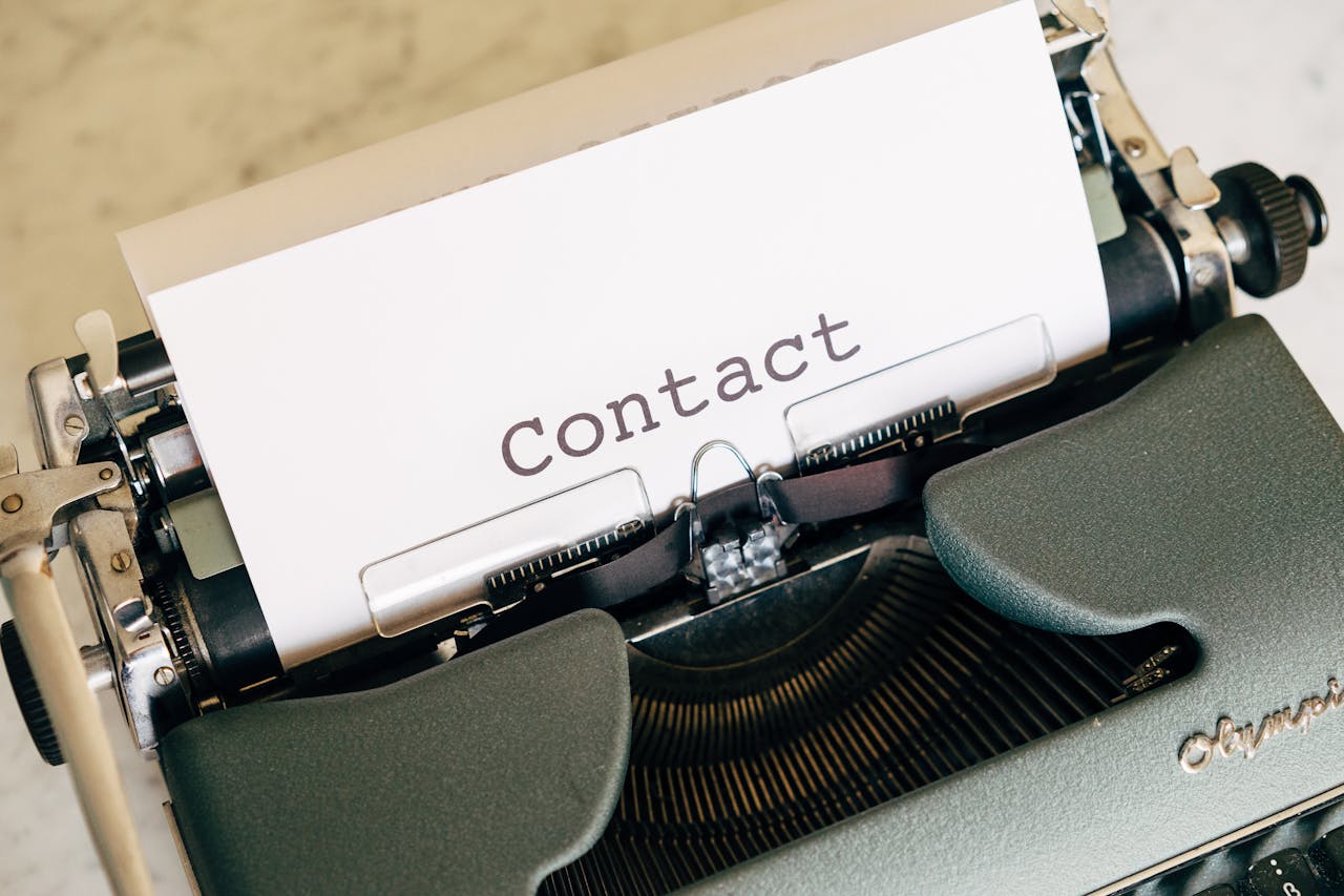 Close-up of a vintage typewriter with paper displaying the word Contact.